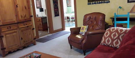 Comfortable living room with TV in amoire, leather recliner, sofa, desk.

