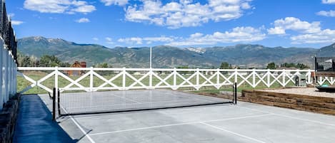 The pickleball court is located to the left of the back deck of the house.