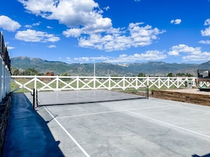 The pickleball court is located to the left of the back deck of the house.