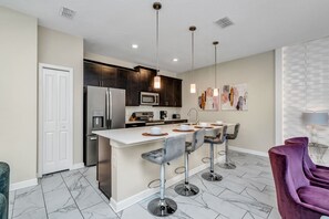 Modern Kitchen of the Townhouse in Kissimmee Florida - Contemporary design with clean lines and minimalist aesthetics - High Chairs and breakfast bar - Thoughtful placement of kitchen essentials for easy access