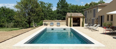 Repos à l'ombre de la pergola sur la piscine style bassin provençal