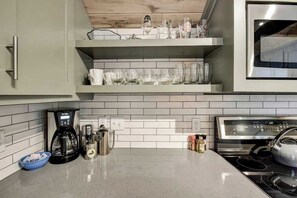 A kitchen with Stainless Appliances, Dishes, and Cookware to make home cooked meals.