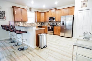 Large fully-equipped kitchen with a bar countertop and four barstools.