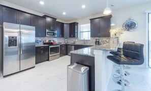 Large fully-equipped kitchen with a bar countertop and four barstools.