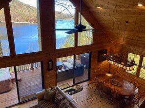 View from the loft area looking down to the dining area, out to the deck & lake