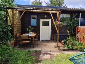 Blick vom Garten auf die überdachte Terrasse und den Eingang zur Wohnung