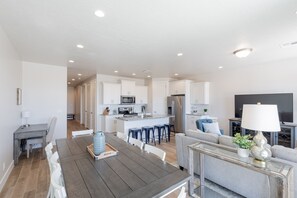 Dining Room View - The Kitchen and Dining Table can accommodate 10 adults and is stocked with pots, pans, baking sheets, mixing bowls, plates, bowls, cups, silverware, and a collection of cooking utensils.