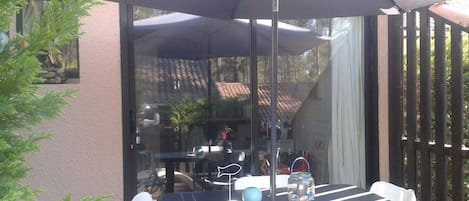 la terrasse avec une table, chaises de jardin et parasol