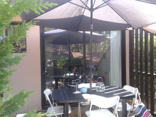 la terrasse avec une table, chaises de jardin et parasol