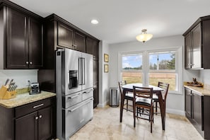 Fully equipped kitchen with stainless steel appliances and seating for 3 people and a bar with 4 stools