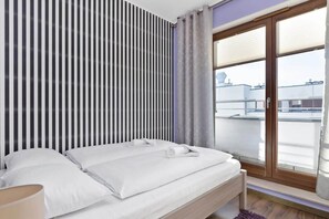A bedroom with a large window and wallpaper with black and white stripes. In the foreground, there is a bed, and the interior is modern and minimalist.