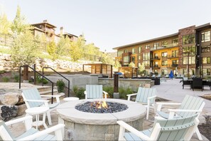 Outdoor circular firepit with white wooden Adirondack chairs, perfect for apres