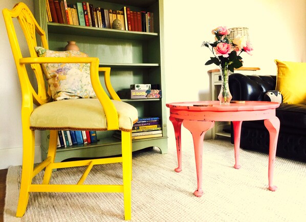 Cosy living area with vibrant, up-cycled furniture and stocked with books/games.