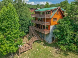 View of the back of the cabin, 3 decks with plenty of seating, hot tub, hammock