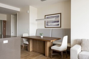 Seating for 10 in the dining nook with solid wood table, upholstered high back dining bench and white upholstered dining chairs with linear pendant chandelier