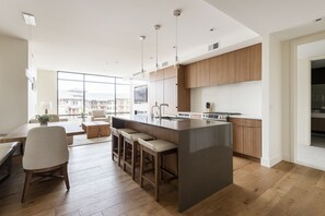 Chef's kitchen with dark quartz kitchen island and bar seating for 3 in leather and wood bar stools