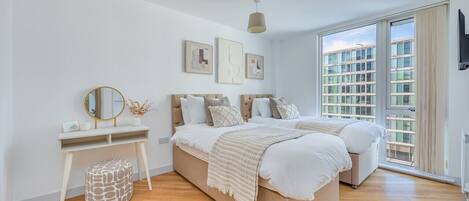 The master bedroom features a large wardrobe, dressing table, smart tv, and a comfortable zip link bed which is configured as two single beds by default or can be zipped together to form a king size bed upon request.