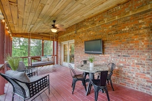 Another angle of the screened porch showing the additional table and chair usage and the wall-mounted TV