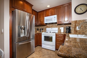 The kitchen features slab granite countertops and rich wood cabiniets.