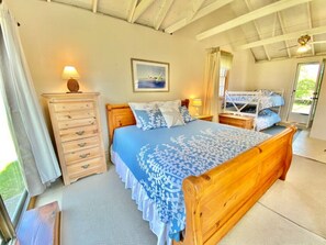 Dune Suite primary bedroom with view towards bunk beds and French door to courtyard with outdoor shower, picnic table and charcoal grill.