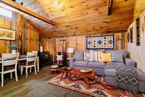 [Barn Loft, Upstairs] Bursting with color, the living room area features western blankets, a fireplace, a mid-century modern rocking chair, and a dining area for 6 individuals.