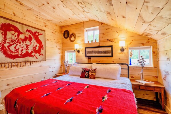 [Primary Bedroom, Upstairs] Secluded at the rear of the barn loft, this room unfolds a scene of southwestern charm, with ample lighting and window views of the animals in the pasture.