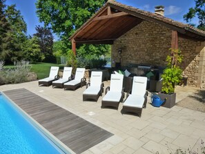 Outdoor kitchen including large BBQ.  Tennis court in the background. 