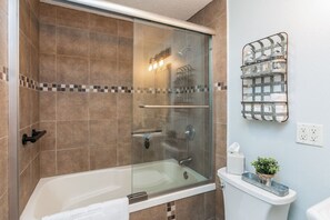 Tiled shower with glass doors and extra deep tub for a relaxing soak.