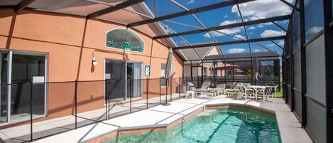 A beautiful shot of your private pool lanai area with a table and loungers.