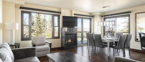 Bright open living room with large windows, dark hardwood floors, and gas fireplace under the flat screen TV