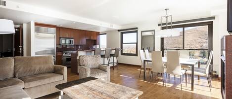 Comfortable living room with two lounge chairs, large coffee table with the dining and kitchen area in the background