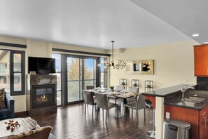 Lowell 304's open concept dining room has 6 chairs and place settings, wood table, and sits next to a gas burning fireplace.