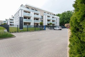 An image showing the modern exterior of the apartment building, surrounded by greenery and well-kept landscaping.