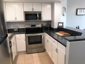 Kitchen that is fully stocked for cooking. Pots and pans, silverware, plates.