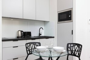 A modern dining table for two, situated near the balcony doors with natural light flowing in.