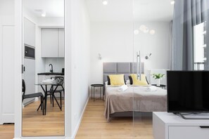 A cozy bed area placed next to the living space with a soft gray curtain for separation.