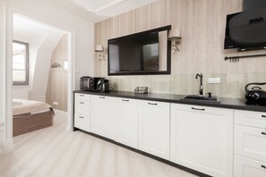 A sleek, modern kitchen with white cabinets and a black countertop. The minimalist design emphasizes functionality and elegance.