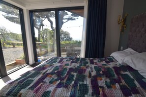 The master bedroom has floor to ceiling windows and a door onto the patio