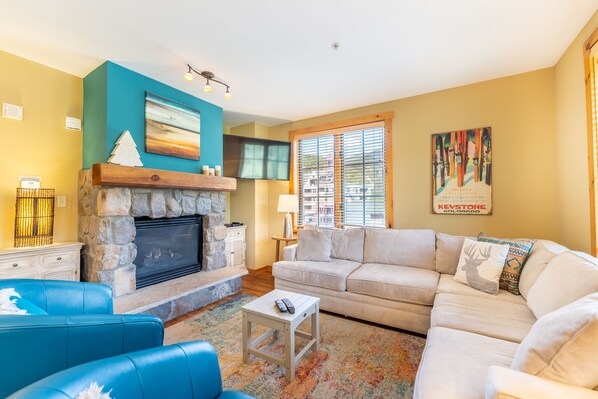 Living area with gas fireplace, mounted flat screen TV, ample seating and hardwood flooring.