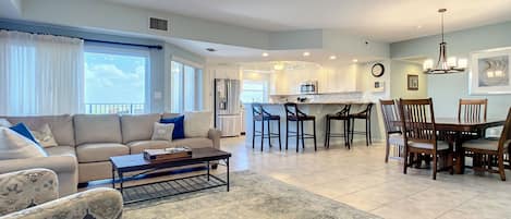 Sofas, ceiling fan, dining table, chairs, and the kitchen with breakfast bar