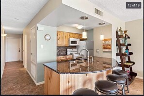 Counter has under cabinet lighting. Custom cabinets and glass tiled back splash.