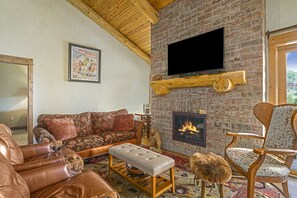 A tv, a fireplace, leather couches and chair