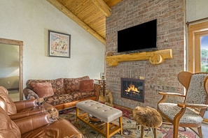 A tv, a fireplace, leather couches and chair