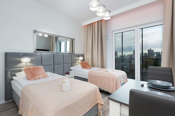 A comfortable space with two single beds on which there is a pastel-coloured bedspread.