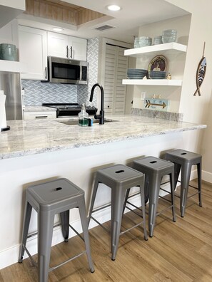 Fully equipped kitchen with granite countertops and ocean themed backsplash.