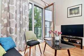 Lounge area with a sofa bed, coffee table, TV and access to balcony.