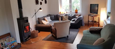 Wohnzimmer mit Kaminofen, 2 Sofas und TV. Zugang vom Flur.