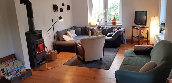 Wohnzimmer mit Kaminofen, 2 Sofas und TV. Zugang vom Flur.