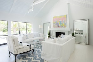 Vaulted ceiling living room with a fireplace and outdoor access.