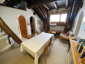 View of the dining table and the living room, the stairs / ladder to the gallery and the two bedrooms on the left